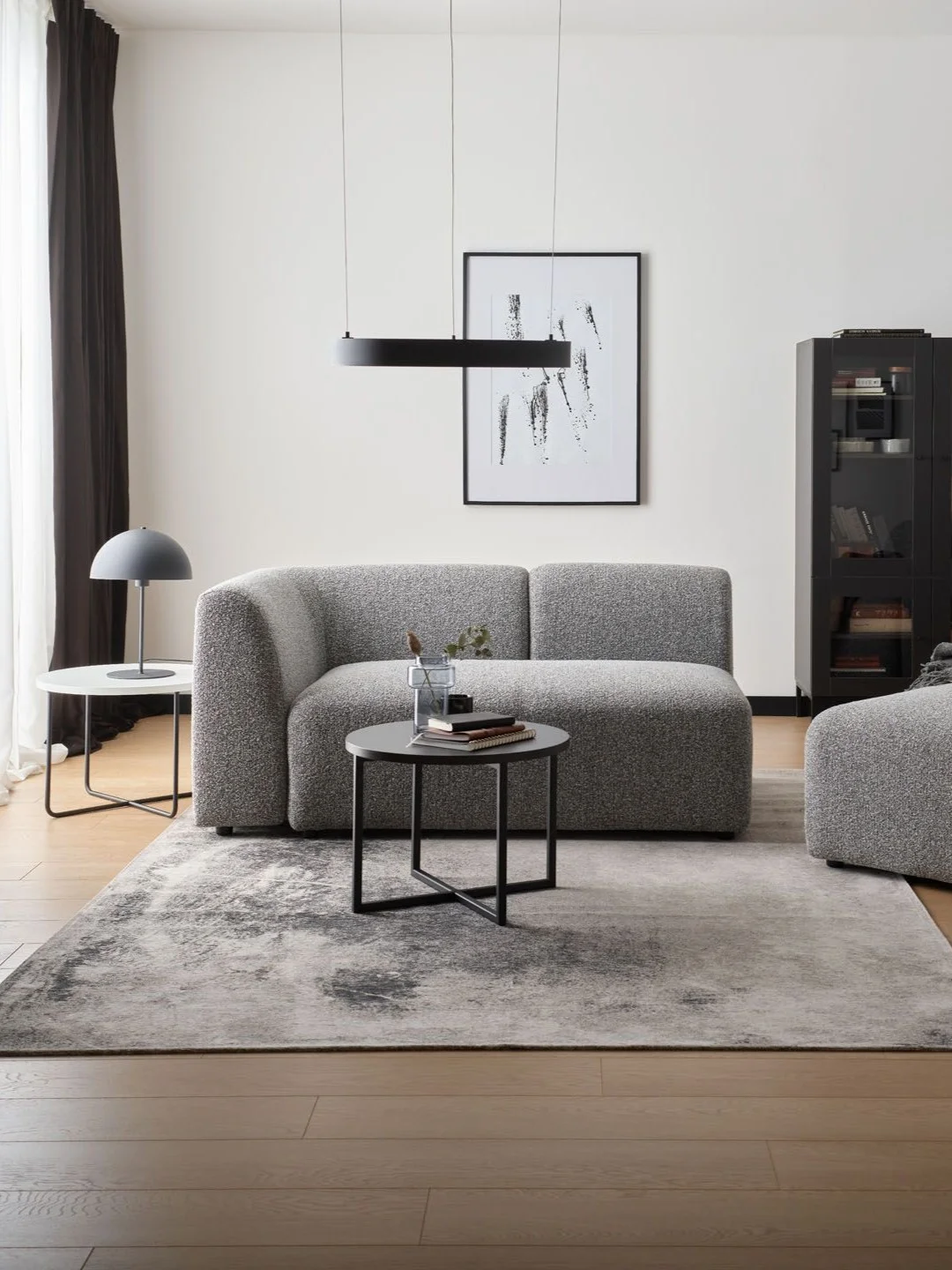 Nowoczesna szara sofa w minimalistycznym wnętrzu z czarnymi akcentami.